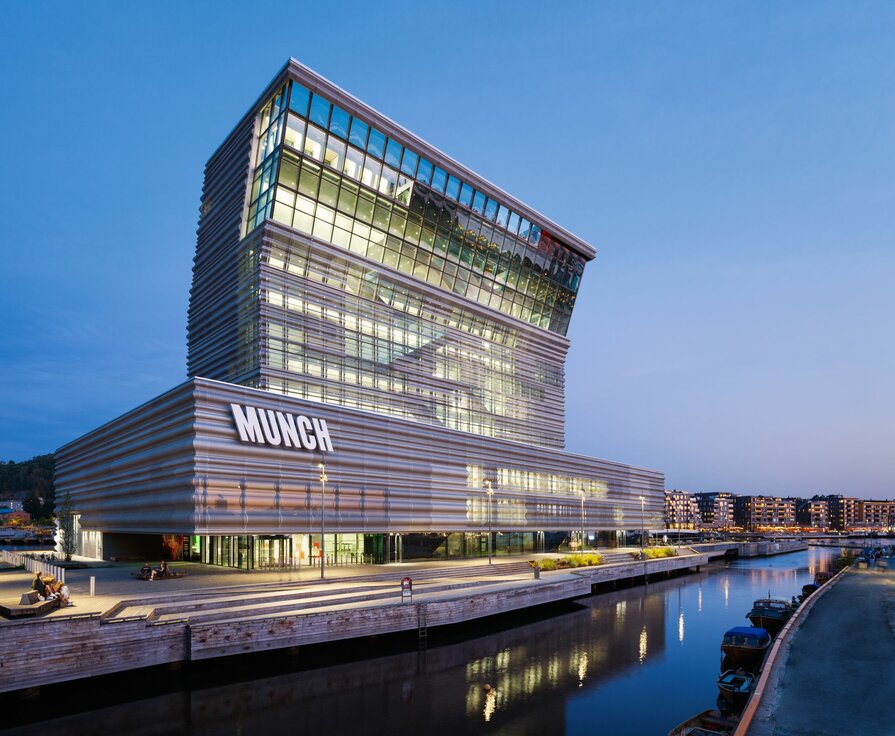 MUNCH Museum Oslo mit wellenförmiger Aluminiumfassade und Glasfront bei Abenddämmerung am Wasser
