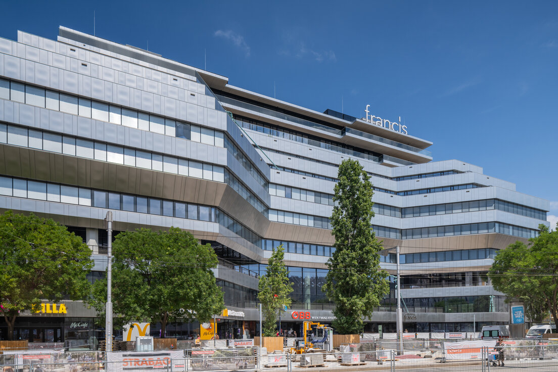 Außenansicht des Bürogebäudes Francis im Althan Quartier Wien mit moderner silberner Glasfassade, großen Fensterflächen und Bäumen im Vordergrund | © © Walter Luttenberger