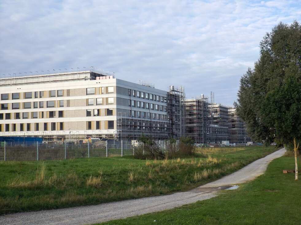 Außenansicht des im Bau befindlichen Flugfeldklinikums Böblingen mit teilweisem Gerüst an der Fassade und Grünflächen im Vordergrund. | © © www.Lindner-Group.com