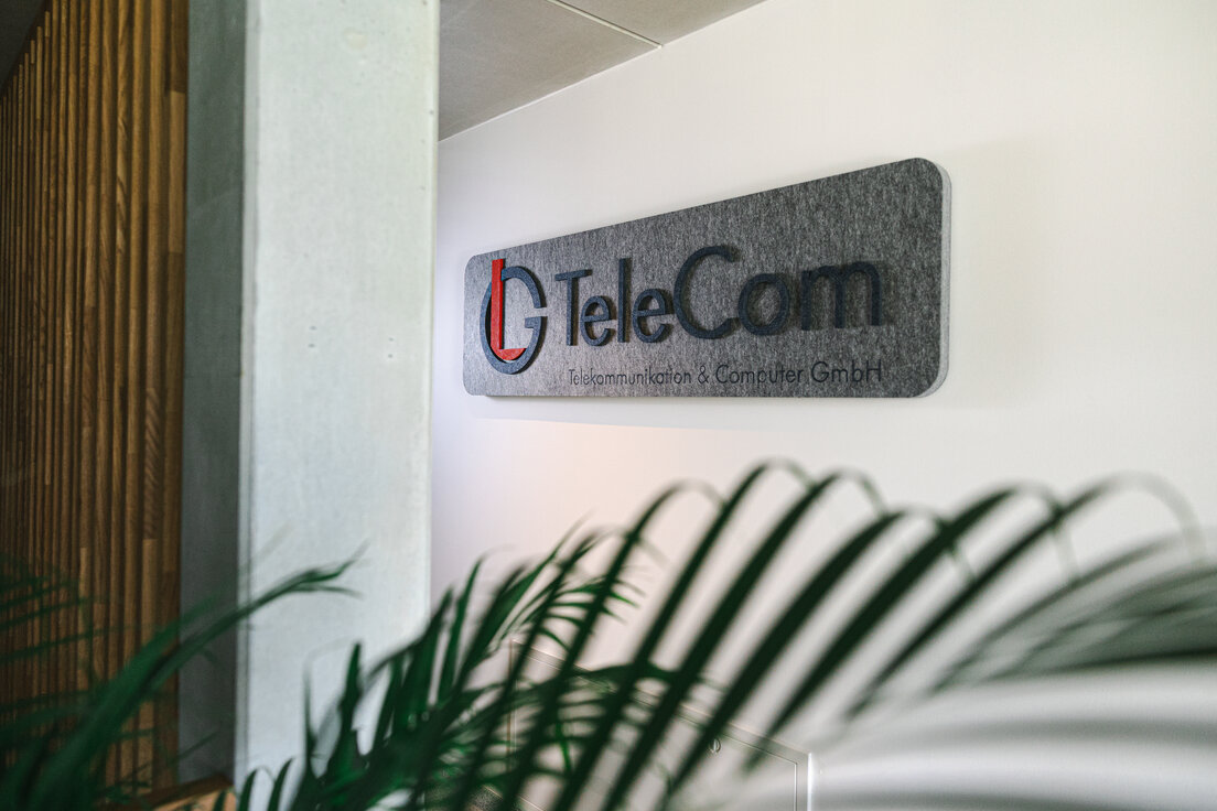 Grauer MUTE+® board Schallabsorber mit aufgedrucktem LG TeleCom Logo an der Wand – individuelle Akustiklösung von Lindner für markenstarke Raumgestaltung. | © © www.Lindner-Group.com