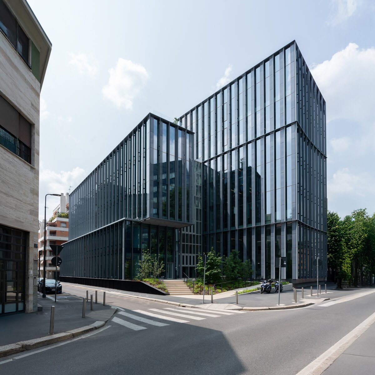 Außenansicht des Bürogebäudes Lybra in Mailand mit markanter Glasfassade an der Via Confalonieri 29 und kreuzender Straße. | © © Paolo Riolzi studio