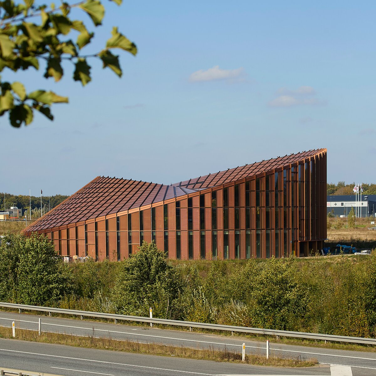 Rundes Dymak Headquarter in Odense mit kupferfarbener Holzfassade von Lindner, nachhaltige Architektur in grüner Umgebung | © © Thomas Mølvig